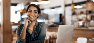 Gerente de um restaurante sorrindo ao lado de um computador com cardapio digital usando o sistema OlaClick