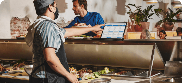 Cuisinière regardant le système de gestion de la cuisine sur un ordinateur