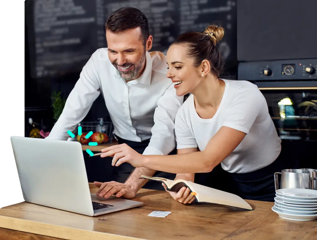 Dos Managers de un restaurante sonriendo mirando al sistema de punto de venta de Olaclick