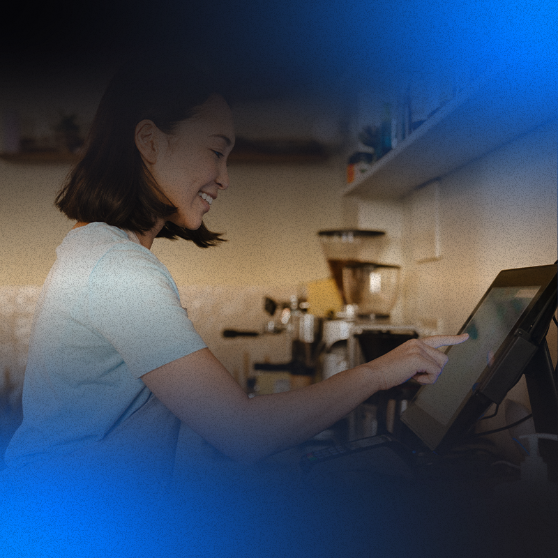 foto de uma atendente sorridente de restaurante gerenciando pedidos no sistema de pdv completo, por meio de um monitor que esta localizado na cozinha
