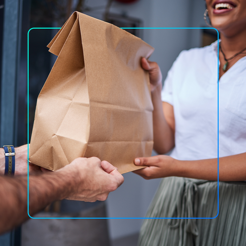 imagem mostra o entregador de comida fazendo a entrega ao cliente que comprou por aplicativo de entrega