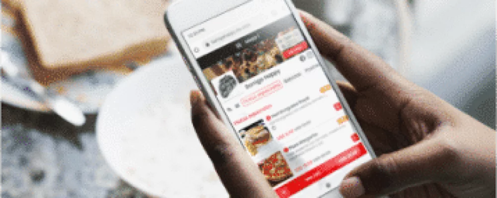 Uma pessoa selecionando produtos de um cardápio digital com o seu celular, para pedir comida pelo cardápio web do sistema de delivery
