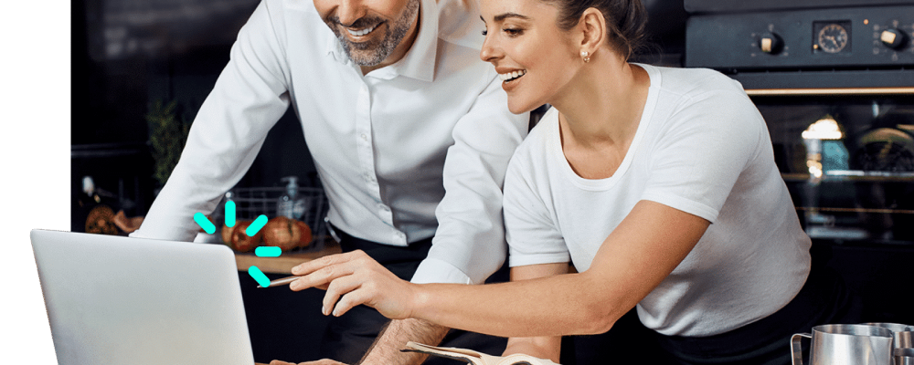 Dos Managers de un restaurante sonriendo mirando al sistema de punto de venta de Olaclick